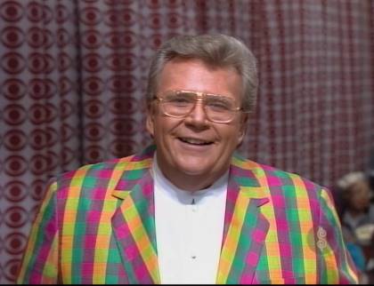 Rod is wearing a multi-colored gingham jacket & white collarless shirt