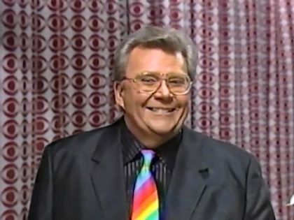 Rod is wearing a black jacket, black-black striped shirt & a rainbow necktie made by a viewer