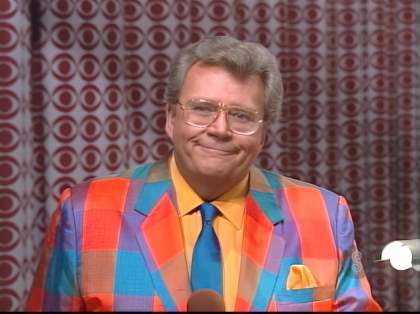 Rod is wearing a multi-colored gingham jacket, blue silk necktie, orange shirt & matching pocket square