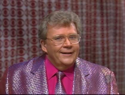 Rod is wearing a shiny purple jacket, matching necktie and fuchsia shirt