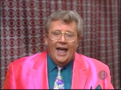 Rod is wearing a silk pink jacket, seafoam-green shirt with matching pocket square & patterned necktie