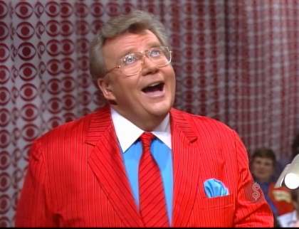 Rod is wearing a red jacket with black pinstripes, matching necktie & turquoise shirt with white collar & matching pocket square