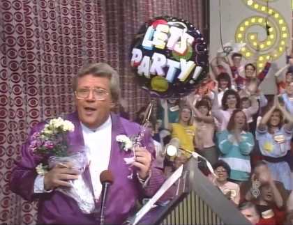 Rod is wearing a purple/violet striped jacket, white collarless shirt & white pocket square