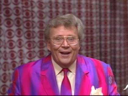 Rod is wearing a pink & purple striped jacket, matching necktie & cream silk shirt with matching pocket square