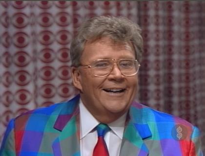 Rod is wearing a multi-color patchwork jacket, matching necktie & white shirt