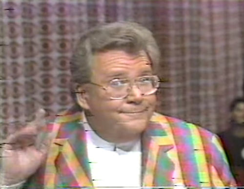 Rod is wearing a multi-colored gingham jacket & white collarless silk shirt