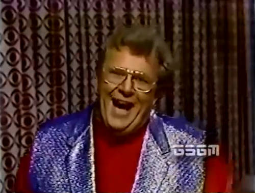 Rod is wearing a shiny purple vest & red collarless shirt