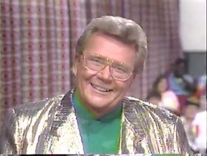 Rod is wearing a gold jacket & green collarless silk shirt w/matching pocket square