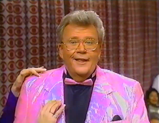 Rod is wearing a shiny pink jacket, matching bowtie & a black shirt with matching pocket square