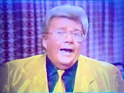 Rod is wearing a shiny yellow jacket, matching necktie & a black shirt