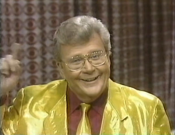 Rod is wearing a shiny yellow jacket, matching necktie & burgundy shirt