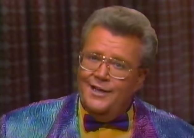 Rod is wearing an iridescent blue/purple jacket, matching bow-tie & mustard-yellow collarless silk shirt
