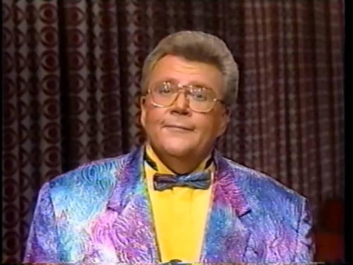 Rod is wearing a blue/purple/pink moiré-patterned jacket, matching bowtie & yellow shirt