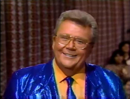 Rod is wearing a shiny blue jacket, matching necktie & mustard-yellow shirt