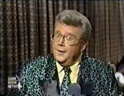 Rod is wearing a shiny green-leopard print jacket with black lapels, matching necktie & yellow shirt