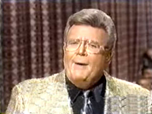 Rod is wearing a gold jacket, tie & black silk shirt