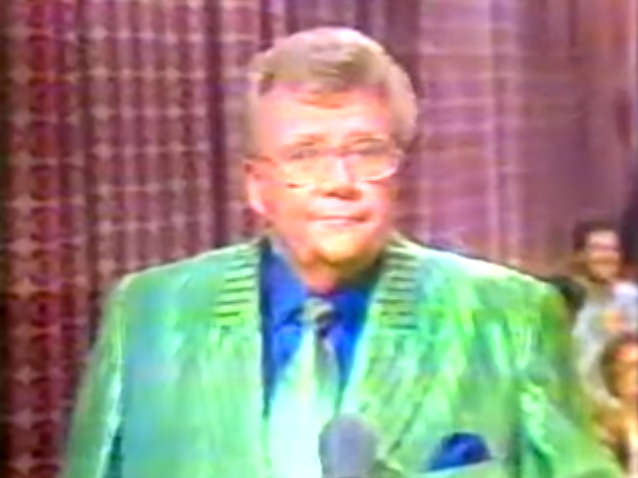 Rod is wearing a shiny green/green-striped jacket & matching tie, blue silk shirt with matching pocket square