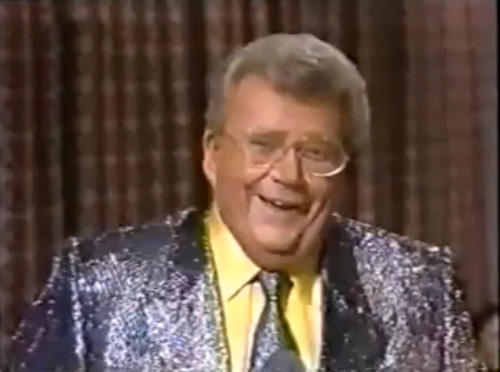 Rod is wearing a purple sequined jacket, matching neck tie & yellow shirt