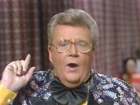 Rod is wearing a black jacket with a silver-fern pattern and black lapels, yellow collarless silk shirt and a black ruffled necktie