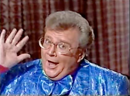 Rod is wearing a shiny blue/blue-striped jacket, matching frilly bow tie & fuschia shirt