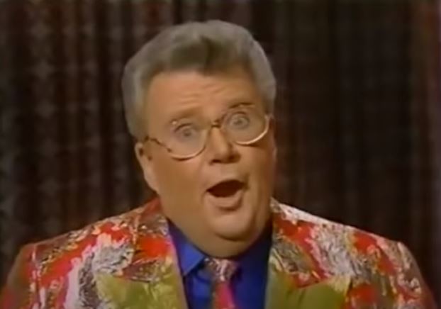 Rod is wearing a red jacket with silver leaves & gold lapels w/ matching tie & blue silk shirt