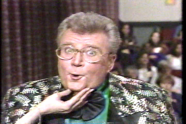 Rod is wearing a black jacket with a shiny-leaf pattern and black lapels, a black frilly bow tie & green shirt