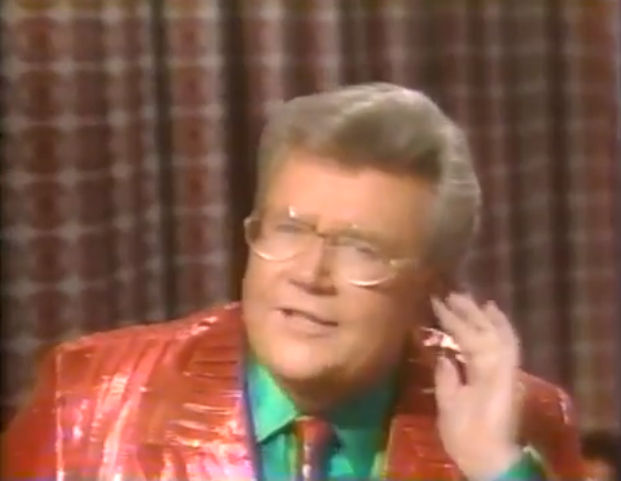 Rod is wearing a shiny red/red-striped jacket, matching tie & green silk shirt