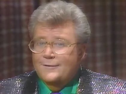 Rod is wearing a silver sequined jacket, green shirt & purple neck tie