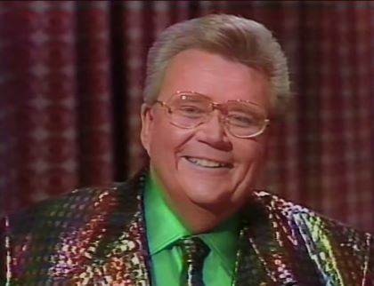 Rod is wearing a shiny oil-slick colored jacket, matching necktie & green silk shirt