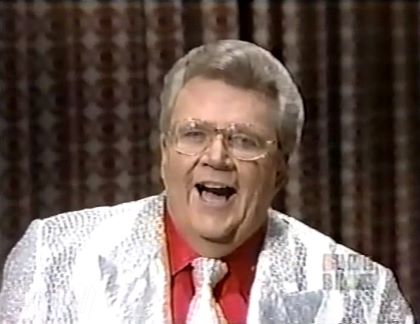 Rod is wearing a silver sequined jacket, matching necktie & a red shirt