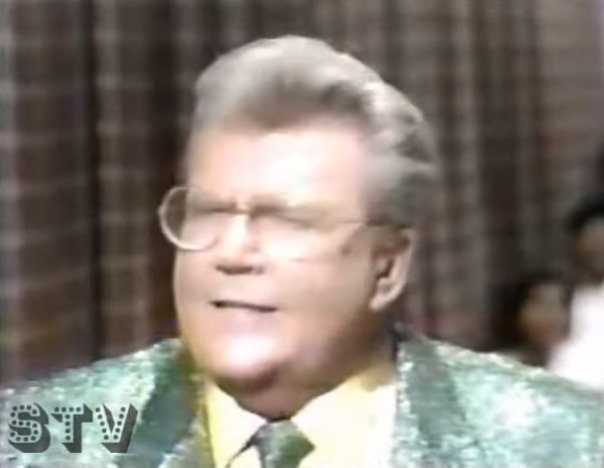 Rod is wearing a green sequined jacket, matching tie & yellow shirt
