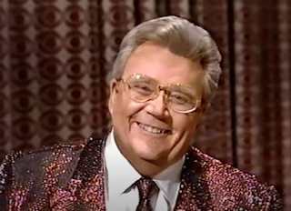 Rod is wearing a red-sequined jacket, matching tie & white shirt