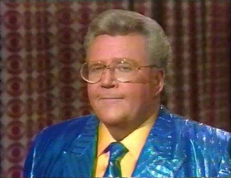 Rod is wearing a shiny blue/blue-striped jacket with matching necktie & yellow silk shirt