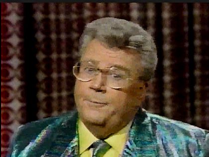Rod is wearing a shiny green & grey striped jacket, matching tie & yellow shirt
