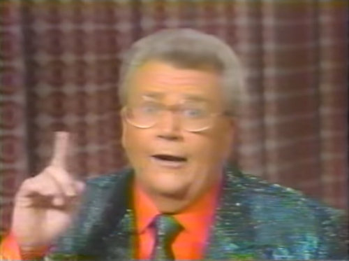 Rod is wearing a dark-green sequined jacket, matching neck tie & red shirt