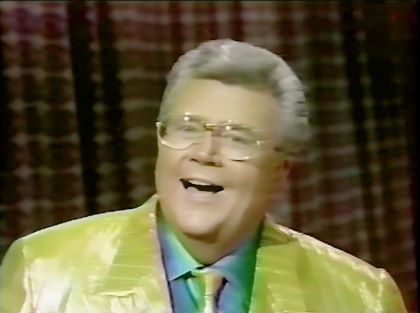 Rod is wearing a shiny yellow/yellow-striped jacket, matching necktie & green silk shirt