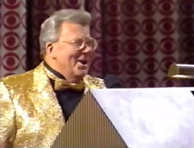 Rod is wearing a gold sequined jacket & matching bow-tie with a black collarless silk shirt