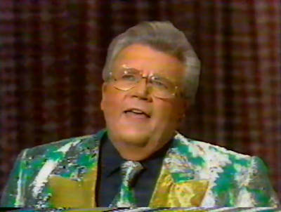 Rod is wearing a shiny green jacket with silver oak-leaves & gold lapels, a matching necktie & black shirt