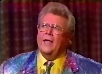 Rod is wearing a shiny blue/purple gradient jacket, matching necktie & yellow collarless silk shirt