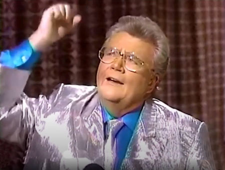 Rod is wearing a shiny silver jacket, matching neck tie & blue silk shirt