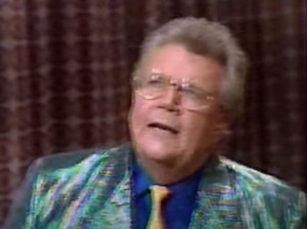 Rod is wearing a shiny green/blue/orange-striped jacket, yellow tie & blue silk shirt