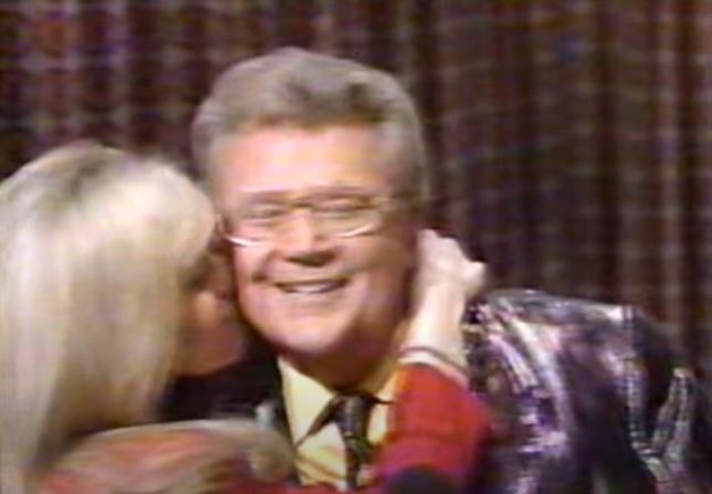 Rod is wearing a shiny purple jacket with matching tie & yellow silk shirt