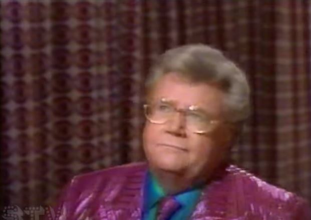 Rod is wearing a shiny purple/purple striped jacket w/ matching tie & blue shirt