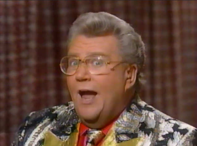 Rod is wearing a black jacket with silver flowers (and matching necktie) & gold lapels with a red shirt