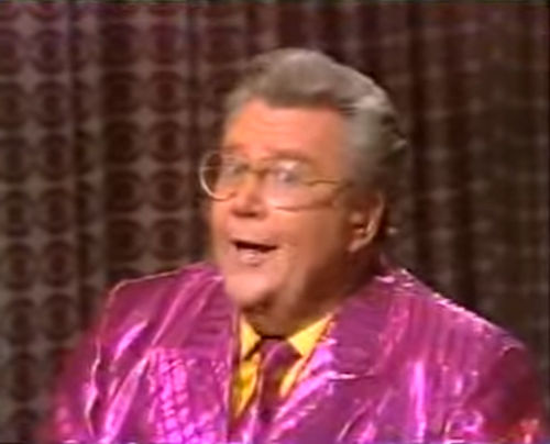 Rod is wearing a shiny fuchsia/fuchsia-striped jacket, matching necktie & yellow silk shirt
