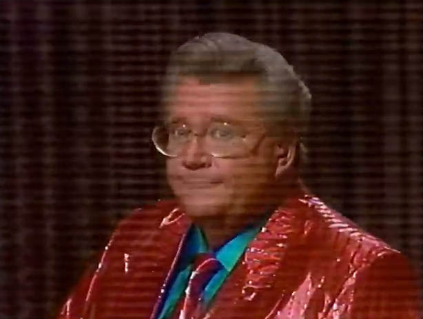 Rod is wearing a shiny red-on-red striped jacket, matching tie & a turquoise shirt
