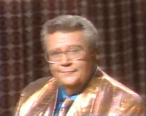 Rod is wearing a gold jacket & tie with a blue shirt