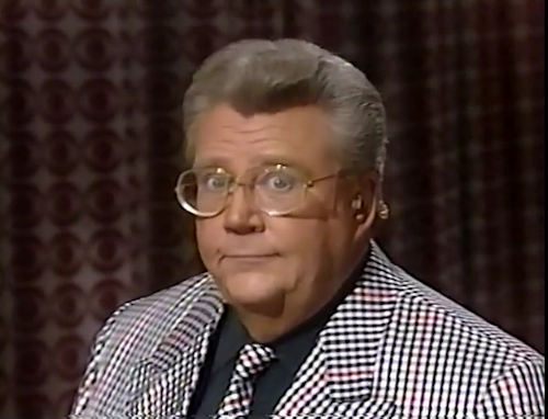 Rod is wearing a black and white gingham jacket, matching tie & black shirt