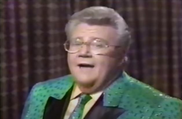 Rod is wearing a green jacket with shiny green dots, black lapels and a matching tie & yellow shirt