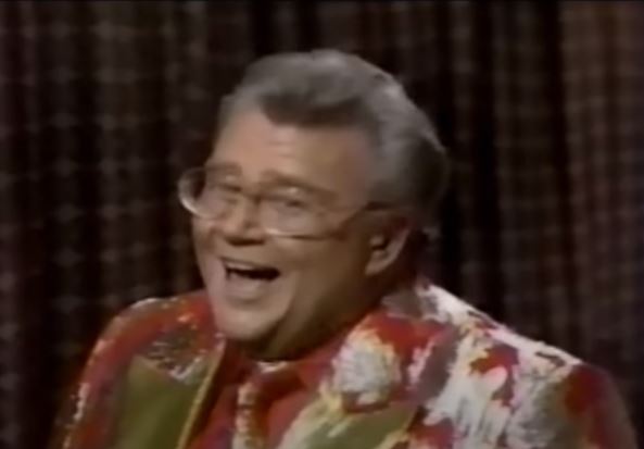 Rod is wearing a red jacket with a silverleaf pattern & gold lapels (with matching tie) & a red shirt